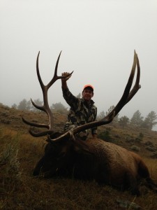 Hunter posing with his bull elk in the rain