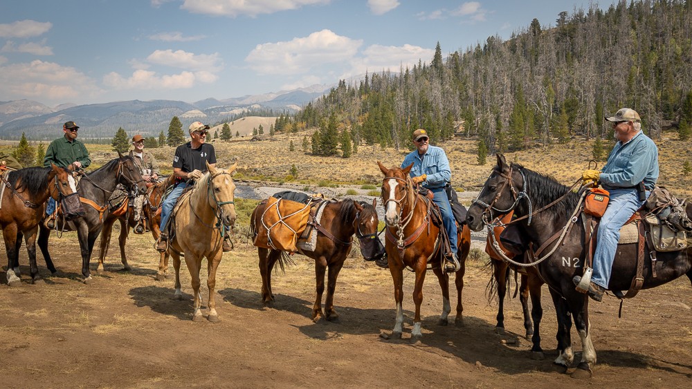 men on horseback about to ride into elk camp