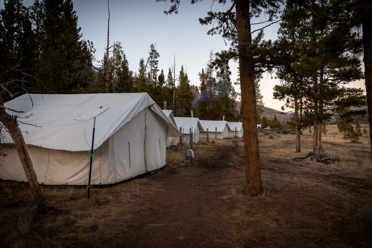a dusky view of wall tents warmed by wood burning stoves at hunting camp in wyoming