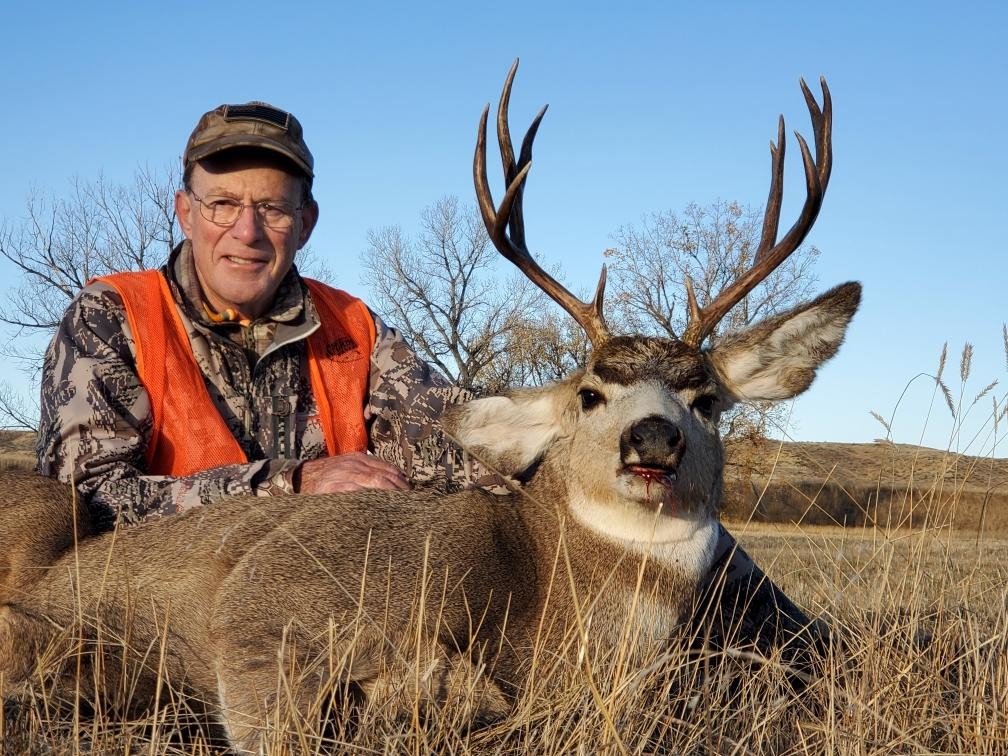A hunter poses with a large mule deer buck in Montana