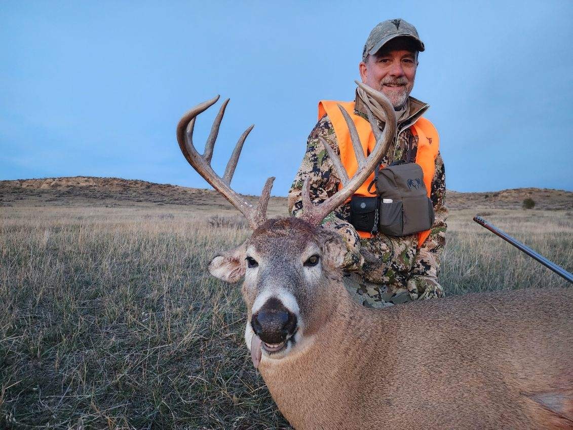 hunter poses with a large whitetail buck deer in wyoming