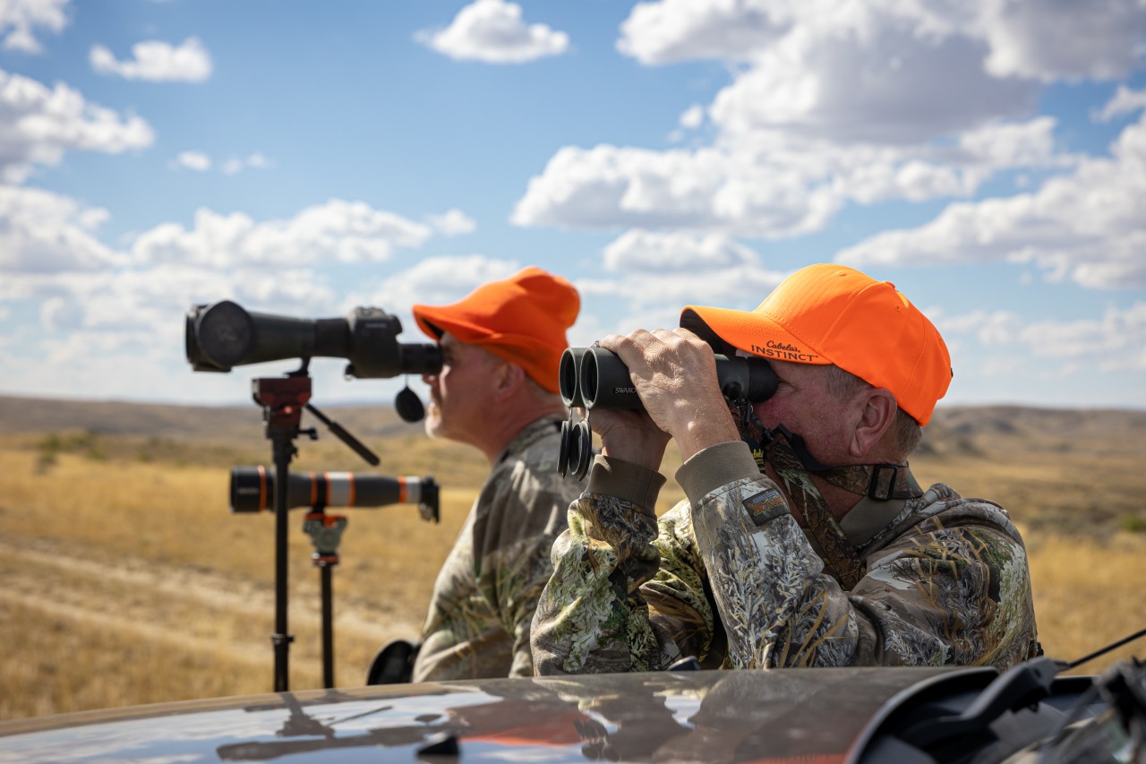 Hunters glass the Wyoming Prairie for antelope wearing camouflage and hunters orange